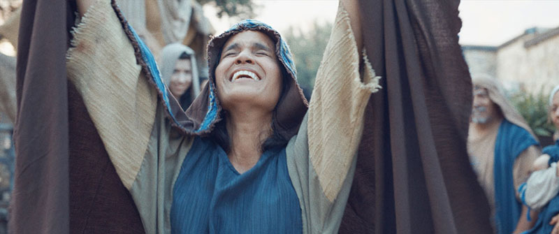 Woman with arms raised in prayer in a scene from ‘JESUS: a Deaf Missions film.’